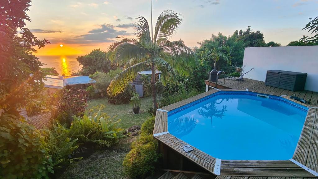 a swimming pool with a sunset in the background at Chez Evelyne et Thierry in Saint-Leu