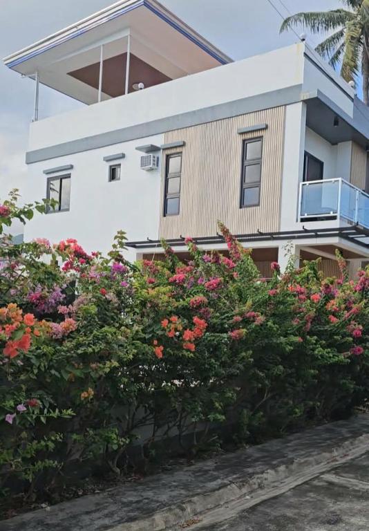 a white house with flowers in front of it at Triple J Villa Puerto Galera in Puerto Galera