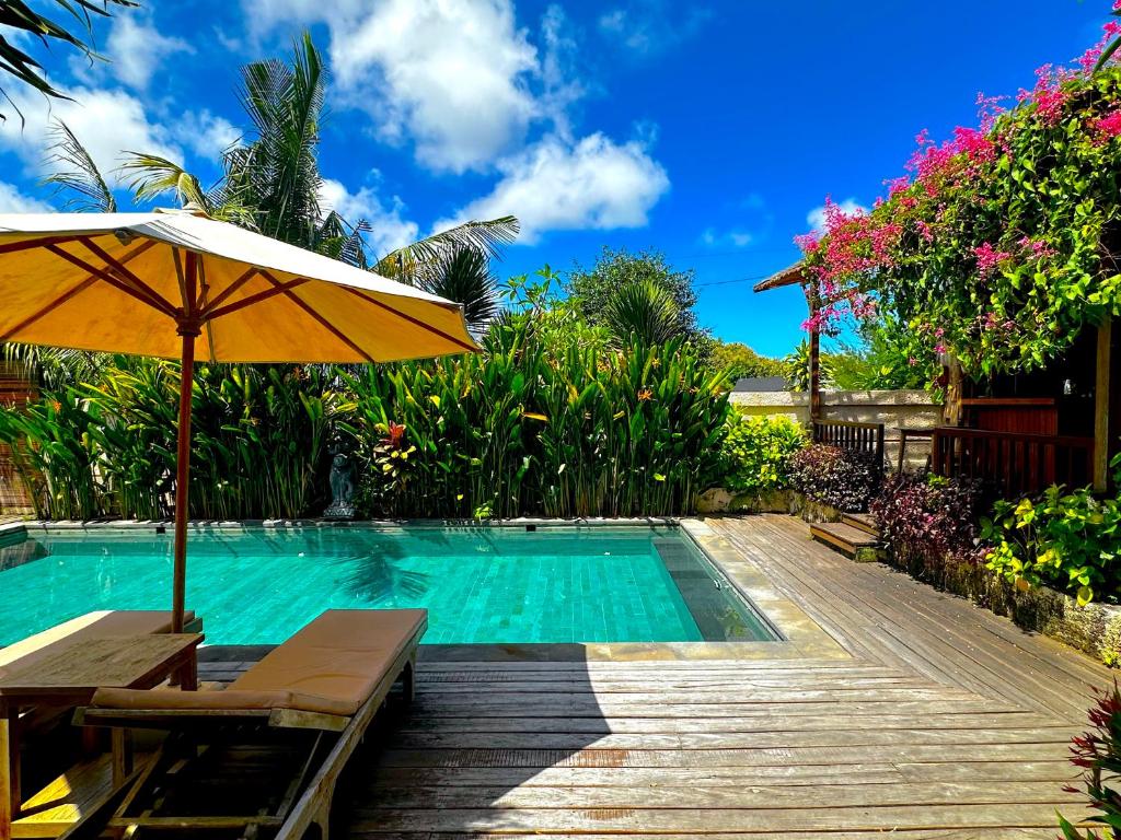 a swimming pool with an umbrella and a table and chairs at Puri Melati in Uluwatu
