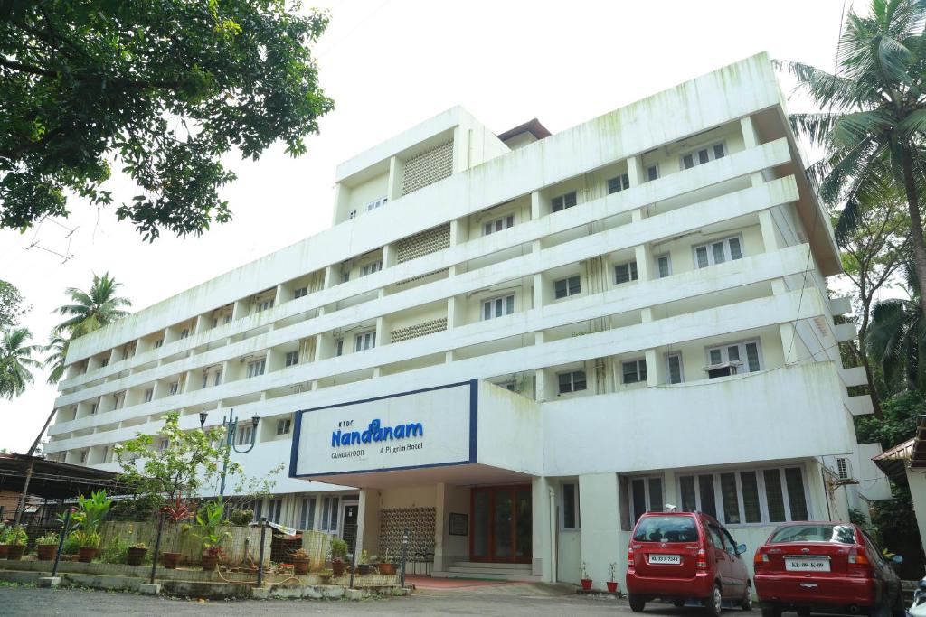 a large white building with a sign on it at Hotel Nandanam in Guruvāyūr