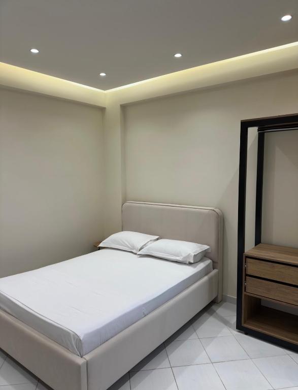 a white bedroom with a bed and a mirror at Xhelilaj Rooms in Vlorë