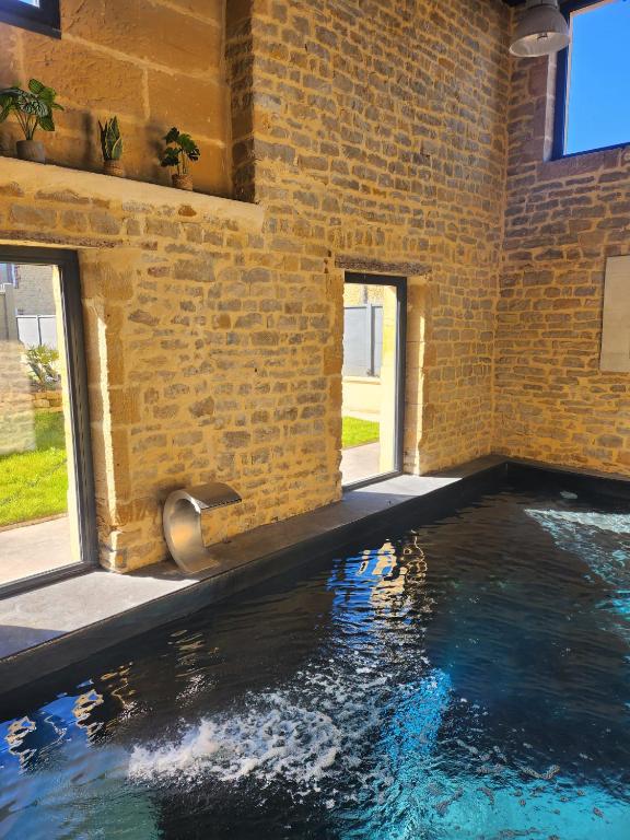 a swimming pool in a brick building with water in it at L'Atypique - Piscine chauffée - Maison en Pierre - Espaces insolites in Floing