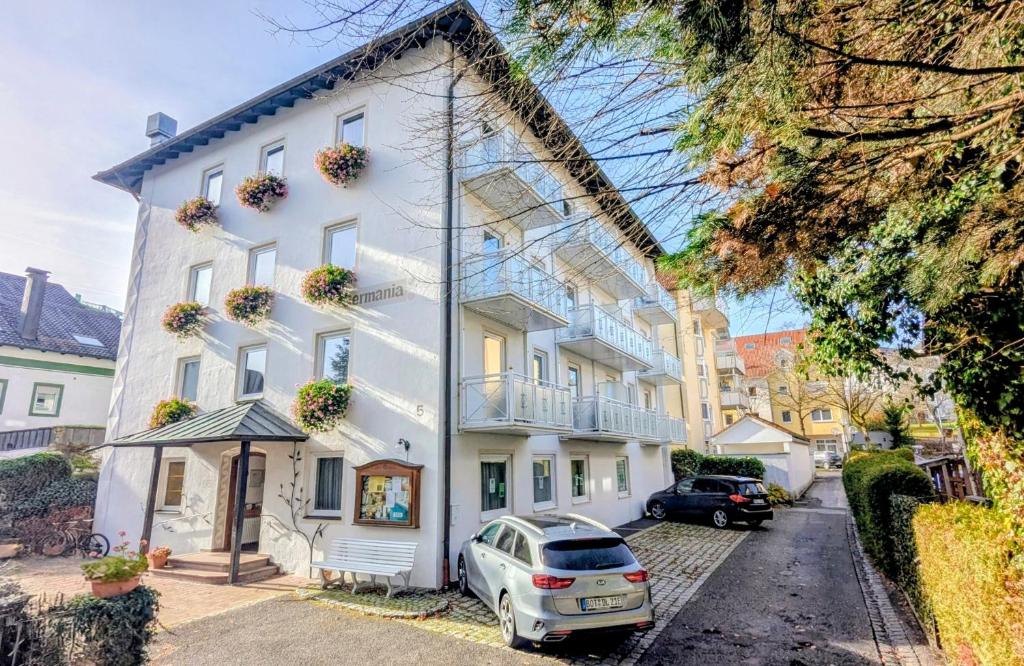 a white house with a car parked in front of it at Hotel Germania in Bad Wörishofen