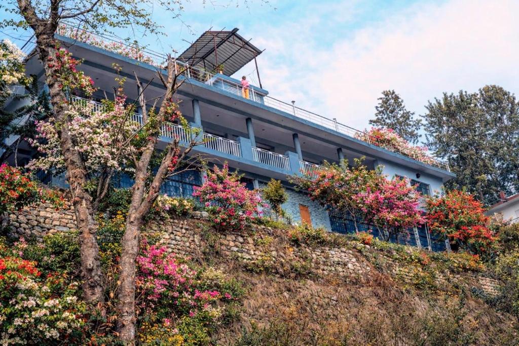 a building with flowers on the side of a hill at Amritganga Homestay in Uttarkāshi