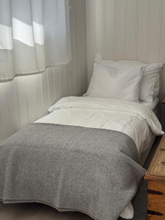 a white bed with a gray blanket on top of it at Sokkelleilighet på Sola in Sola