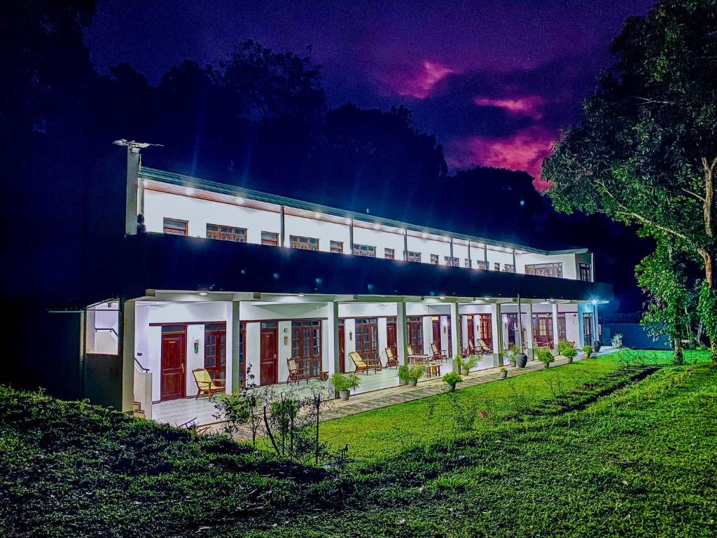 a large white building with red doors at night at Victoria Nature Resort in Digana