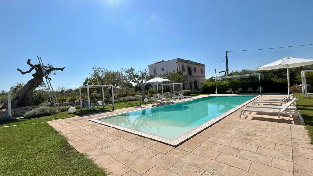 a swimming pool in a yard with umbrellas at Tenuta Pigliano Hotel in Bagnolo del Salento