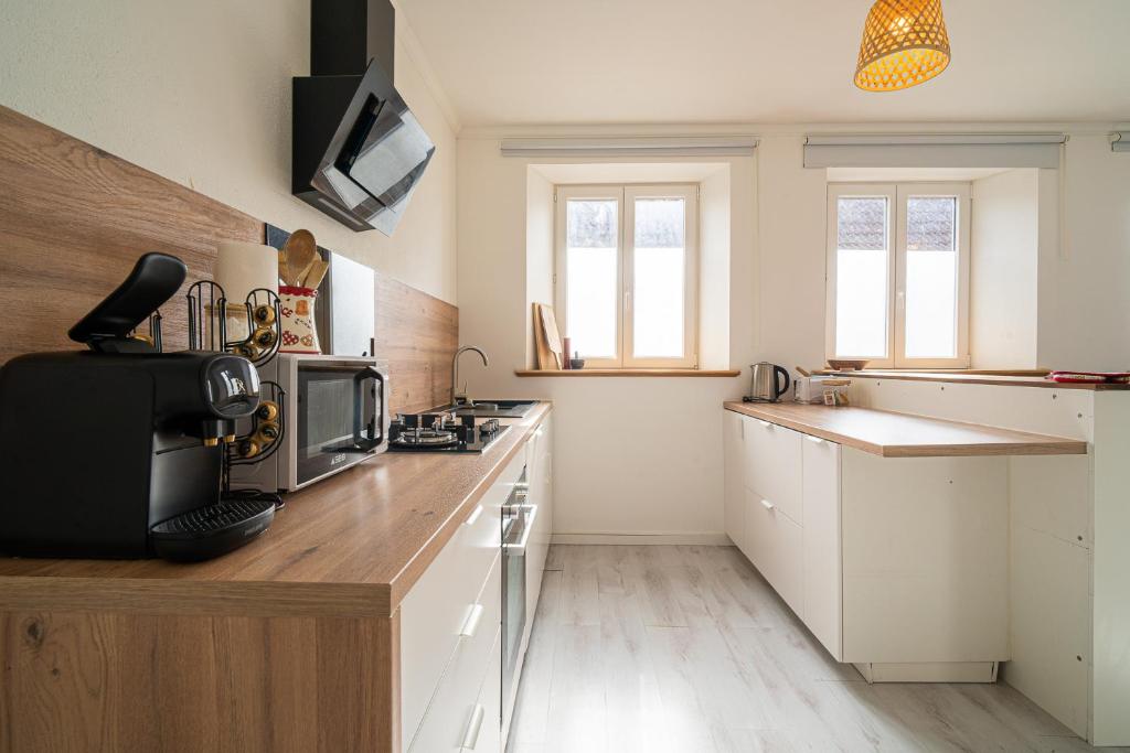 a kitchen with white cabinets and wooden counter tops at Le Cocon Alsacien - Rez de chaussée - Parking privé in Ebersheim