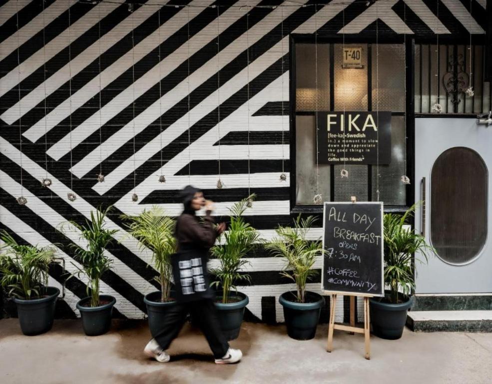 a person standing in front of a building with potted plants at Minimalist One Hauz Khas Village in New Delhi