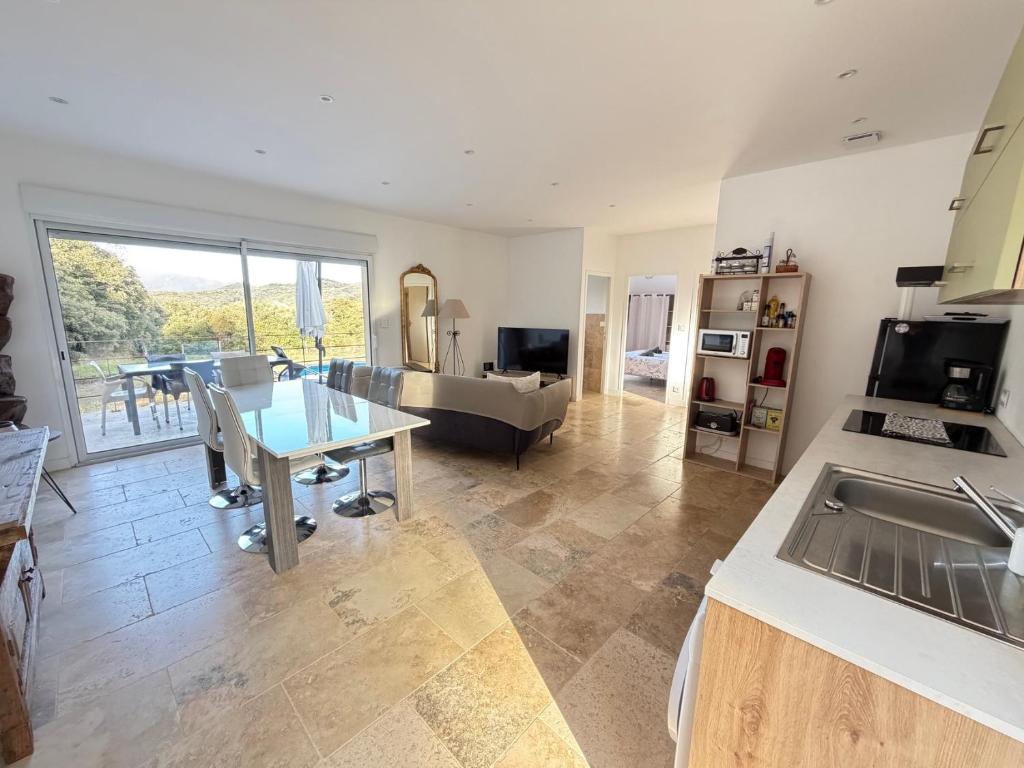 a kitchen and living room with a table and a couch at "Vigna d’Eugène" – T3 Piscine | by Efficios in Petreto-Bicchisano