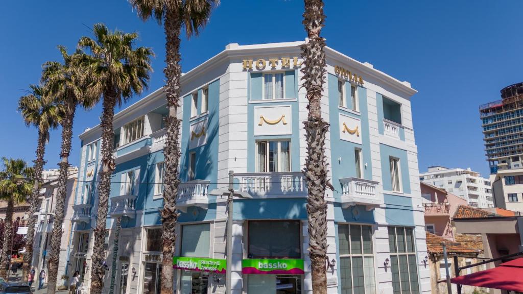 a building with palm trees in front of it at Hotel Giulia in Durrës