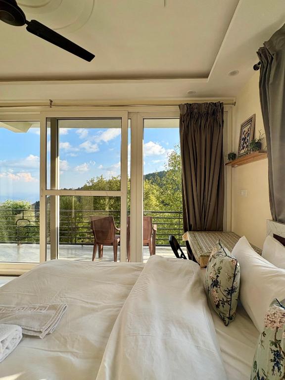 a bedroom with a bed and a large window at Soma House Dharamkot in McLeod Ganj