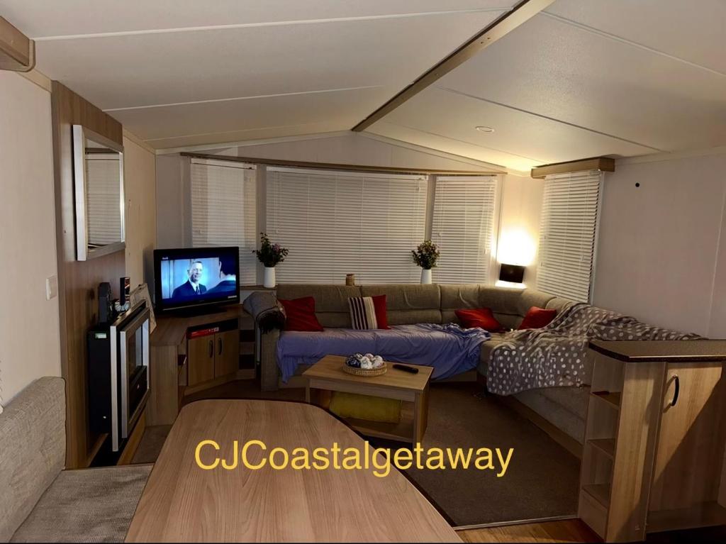 a living room with a couch and a tv at CJ Coastal Getaway #2 in Rhyl