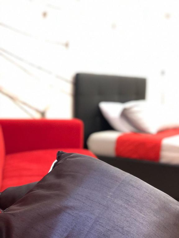a room with two beds and a red couch at Viale Umberto Apartments in Sassari
