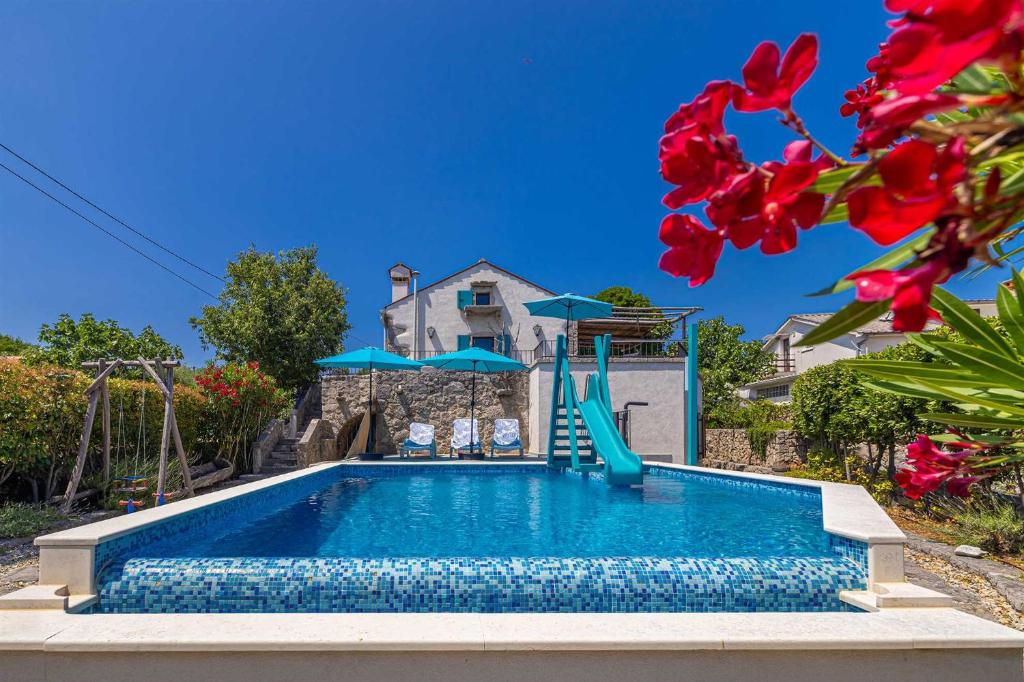 a pool with a slide in front of a house at Rustikalna kuća za odmor VILLA MARE in Kornić