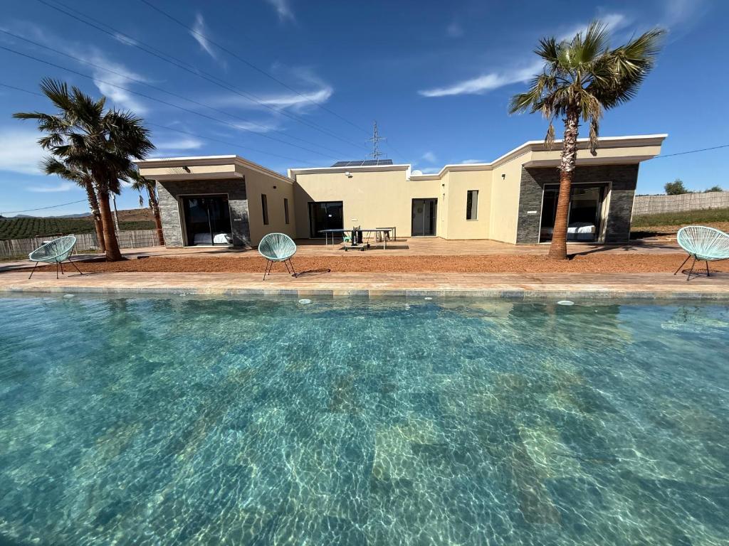 a swimming pool with two chairs and a house at Villa Bonheur - Piscine sans vis-à-vis in Berkane