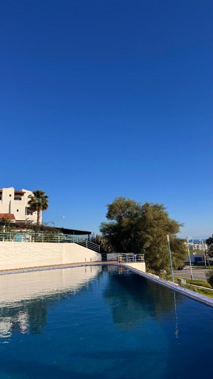 a large pool of blue water next to a wall at Studio moderne soleil piscine wifi à cabonegro in Tétouan