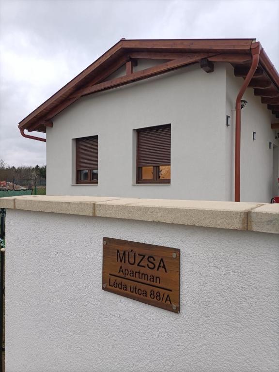 a sign on the side of a white building at Múzsa Apartman in Siófok