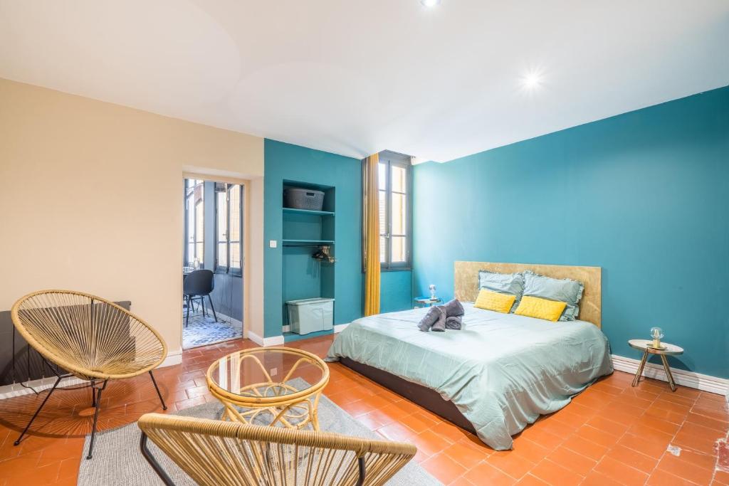 a bedroom with blue walls and a bed and chairs at L’Escapade Nîmoise - grand studio centre Nîmes in Nîmes