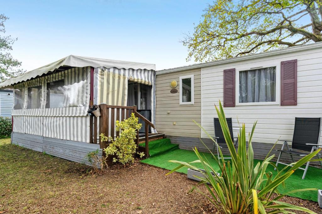 a small white house with a porch and a yard at Mobilehome 5 personnes in Les Mathes