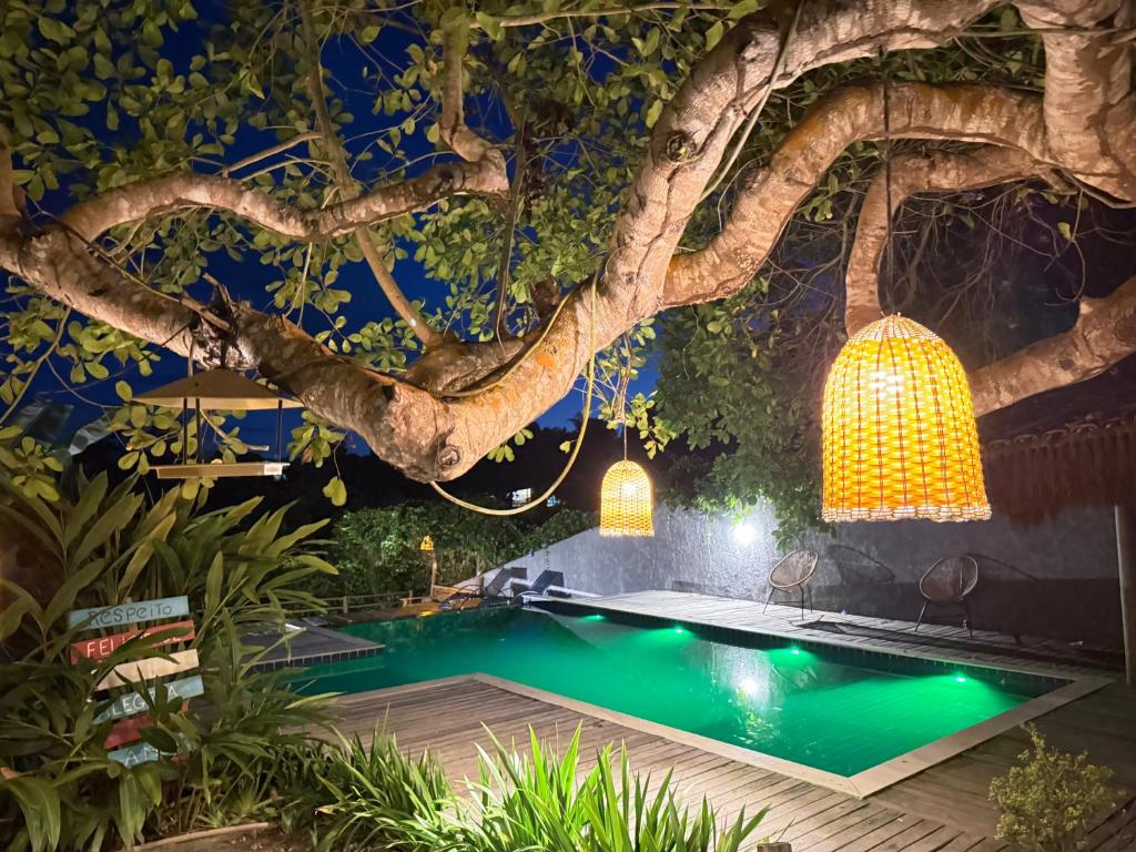 a swimming pool under a tree with lights at Recanto do Villa 1 in Trancoso