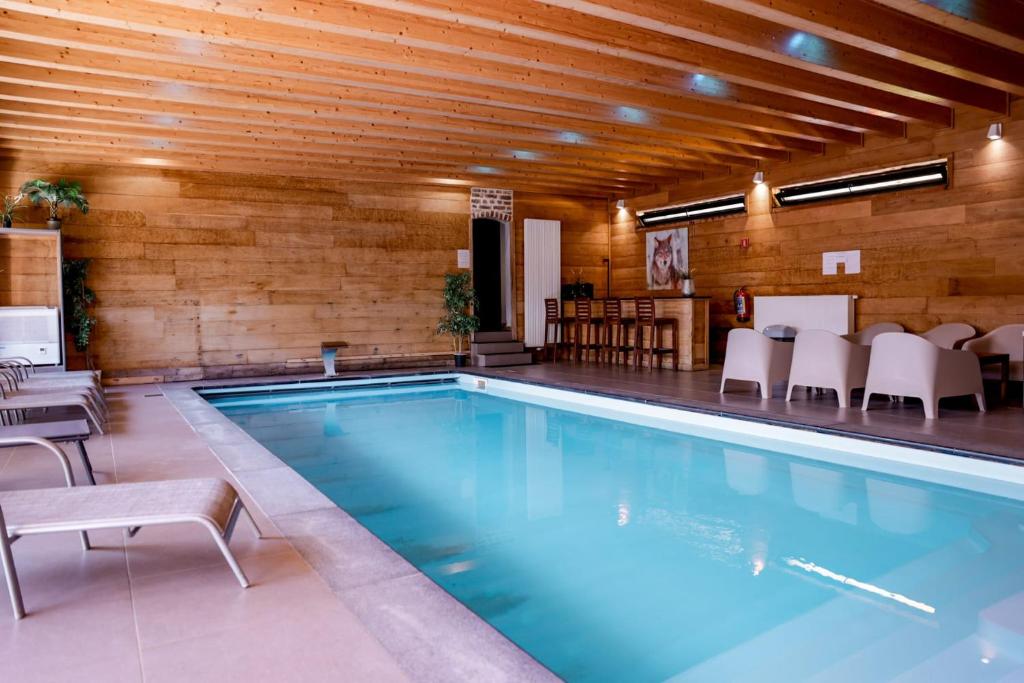 a swimming pool in a building with a wooden ceiling at Le Pays des Sources in Waimes