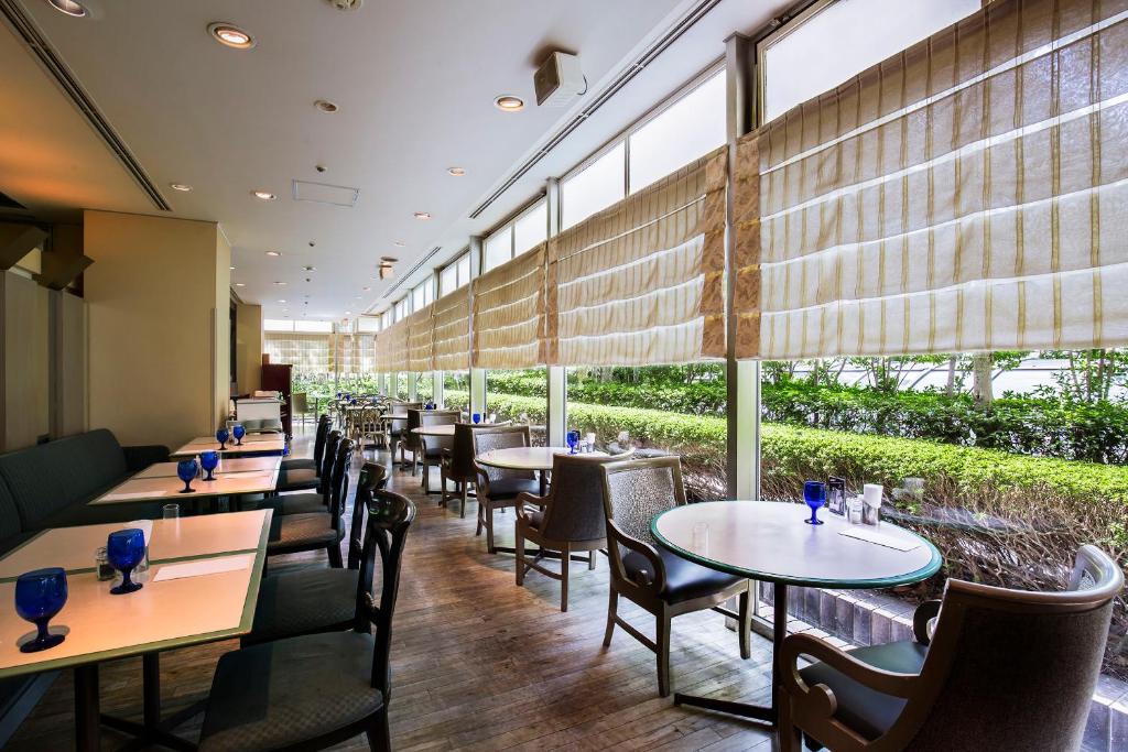 a restaurant with tables and chairs and large windows at New Otani Inn Tokyo in Tokyo