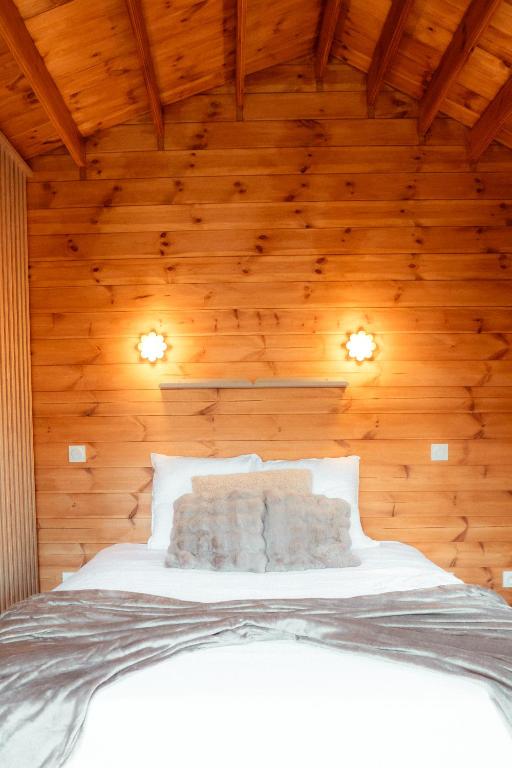 a bedroom with a white bed in a wooden ceiling at Deux Chalets face à la vallée in Chalezeule