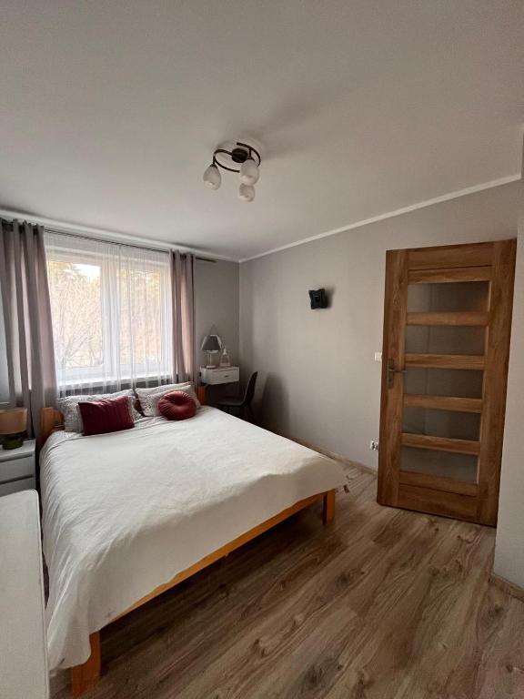 a bedroom with a large white bed and a window at Apart Konopnicka in Augustów
