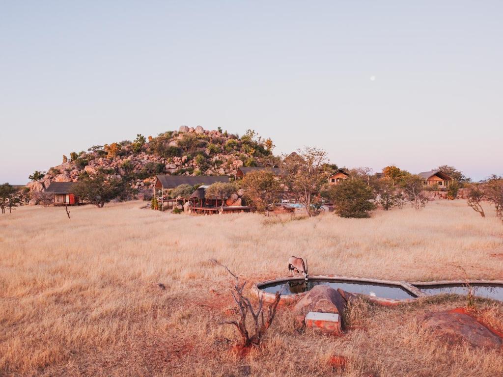 an old car in a field with a house at Ohorongo Tented Camp in Kaneb Pos
