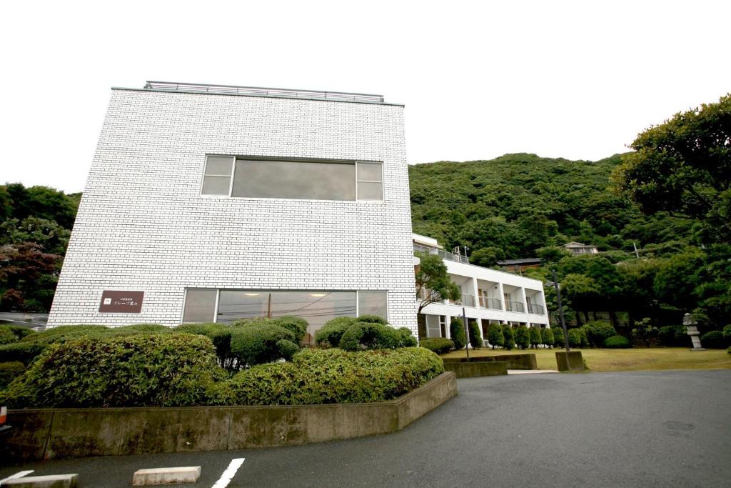 Shiki Resort Prego Hayama في هياما: مبنى من الطوب الأبيض وبه شجيرات أمامه