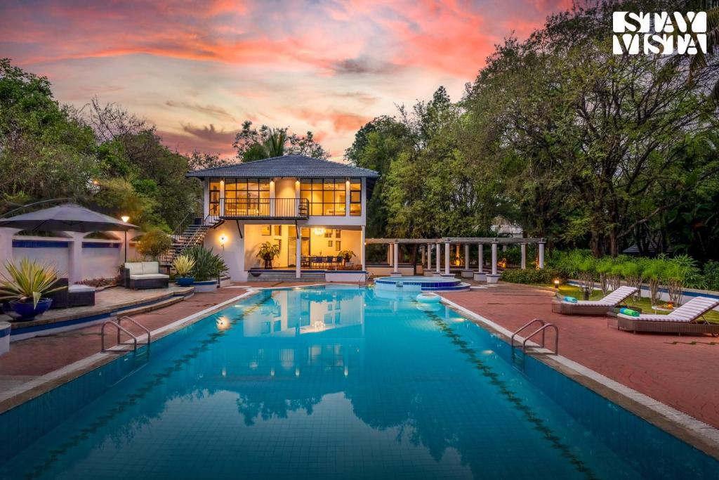 a home with a swimming pool in front of a house at StayVista at Ananta - Breakfast Included & Basketball Court in Bangalore