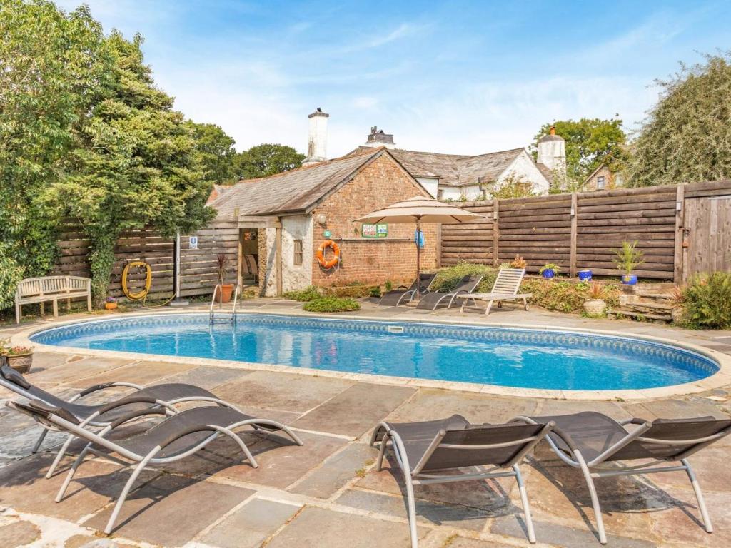 a swimming pool with chairs and a house at 3 Bed in Lifton oc-tcoah in Broadwoodwidger