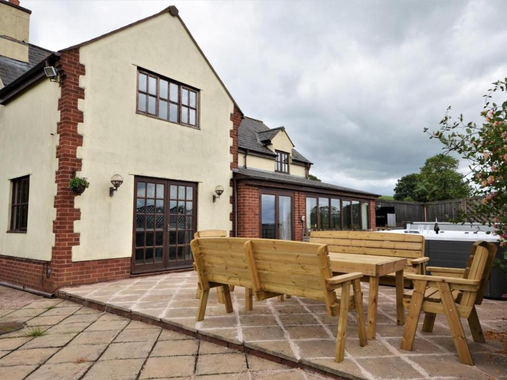 a patio with two wooden benches in front of a house at 4 Bed in Tiverton oc-60110 in Uplowman