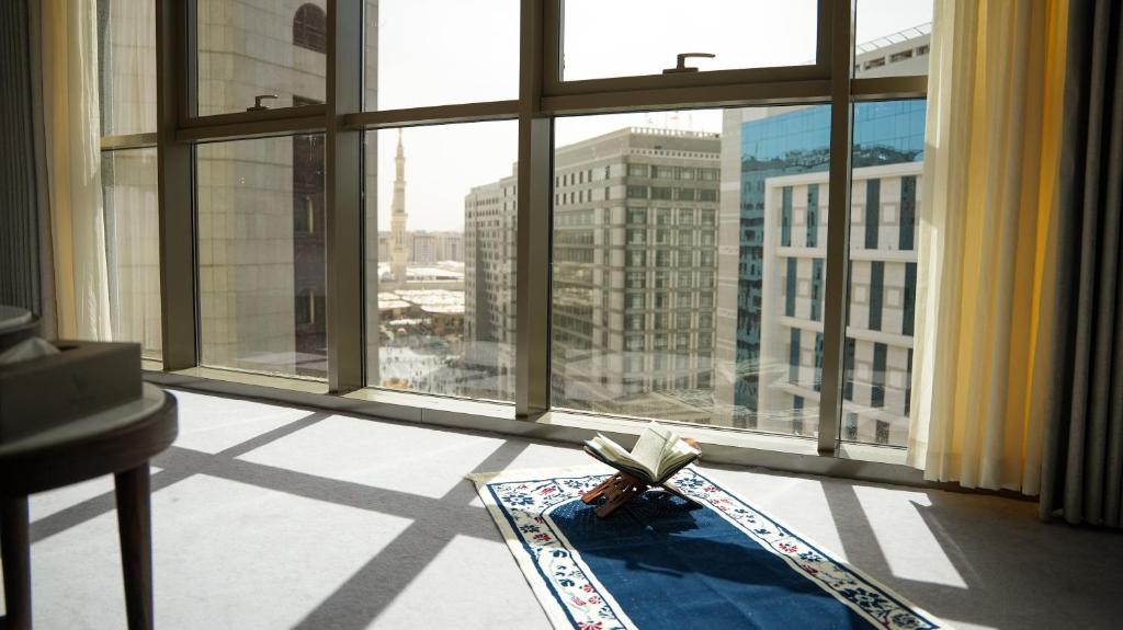ein Zimmer mit einem großen Fenster und Blick auf eine Stadt in der Unterkunft Peninsula Worth Hotel in Medina