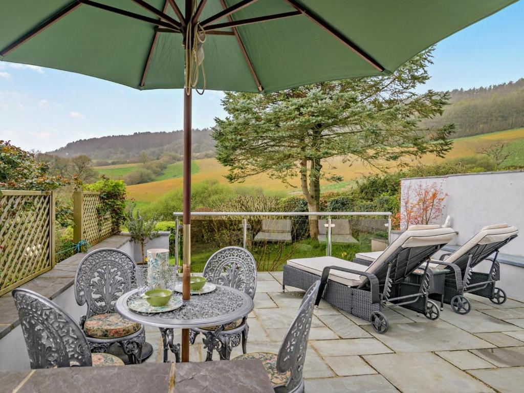 a patio with a table and chairs and an umbrella at 1 Bed in Bridport oc-94617 in Chideock
