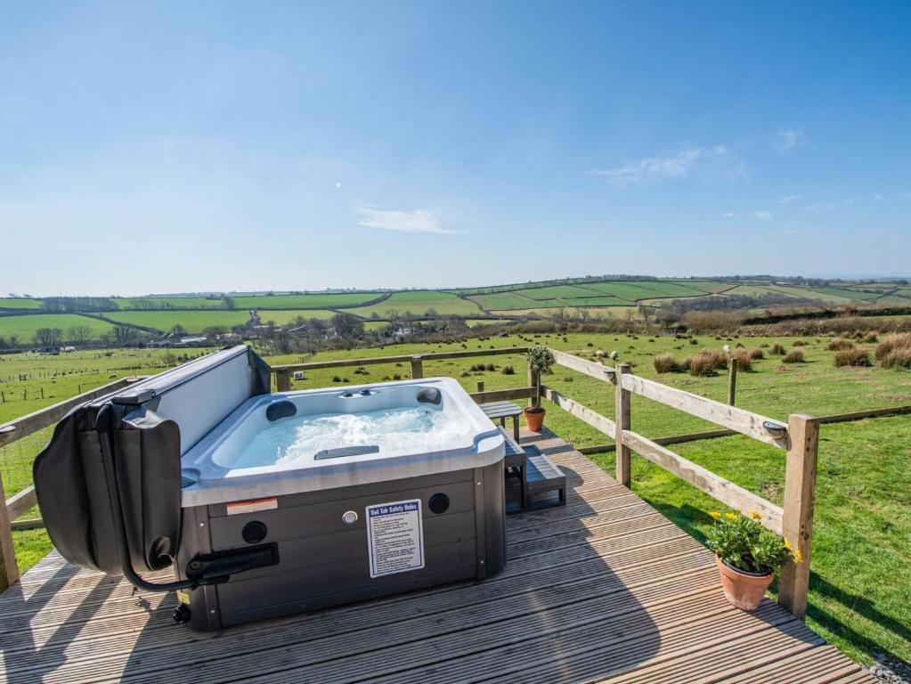 a hot tub on a deck with a view of a field at 1 Bed in Barnstaple oc-90190 in Bratton Fleming