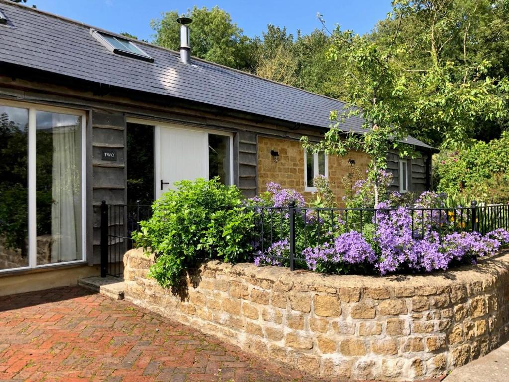 a house with a retaining wall and purple flowers at 2 Bed in Stoke Abbott oc-50884 in Stoke Abbott