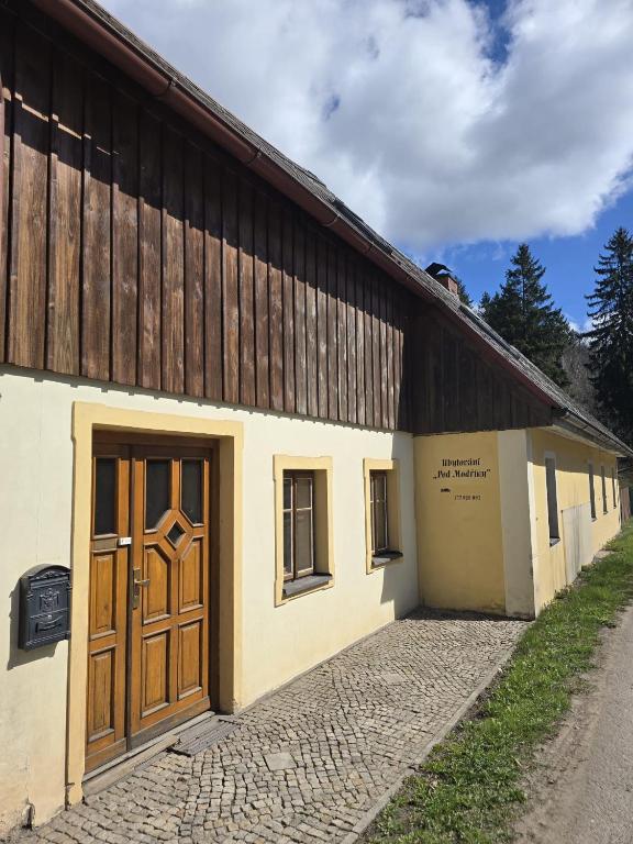 a large building with wooden doors on the side of it at Pod modříny in Adršpach