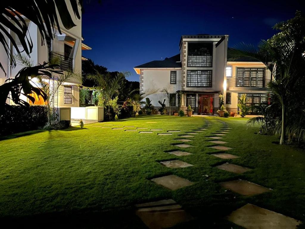 a house with a grass yard with stepping stones at Silva Montana in Mount Kenya