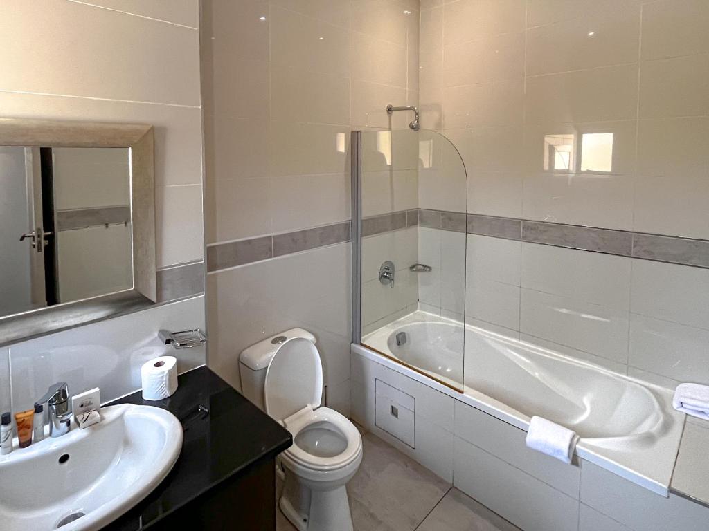 a bathroom with a sink and a toilet and a tub at Golden Crystal Hotel Gaborone in Gaborone