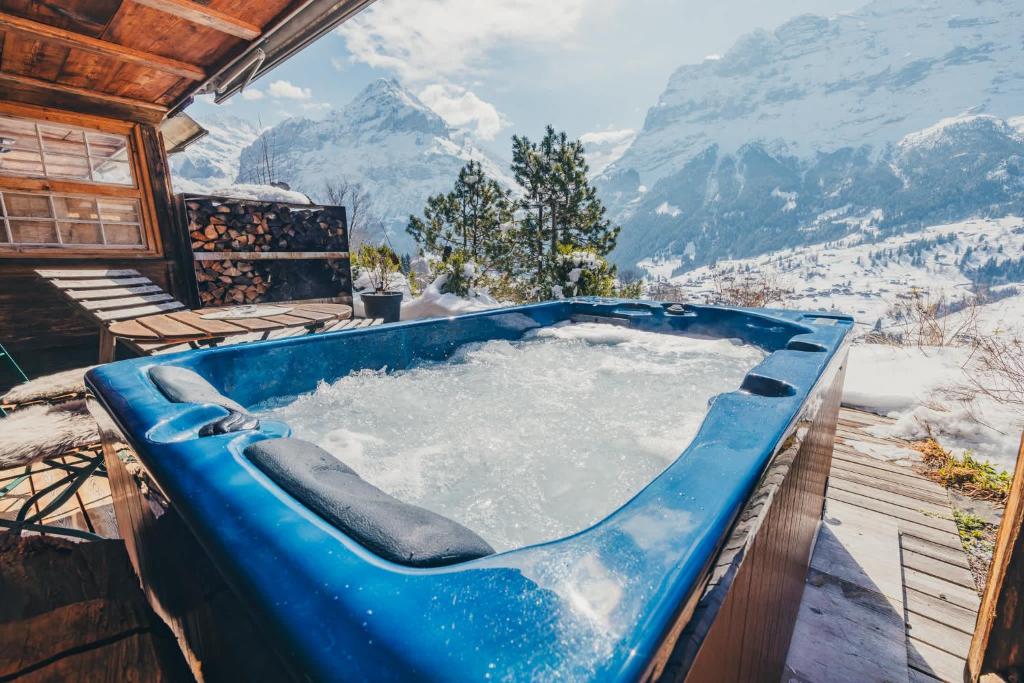 a blue bath tub with a view of mountains at Surfers Sunset Spa with Jacuzzi & Panoramic Terrace in Grindelwald