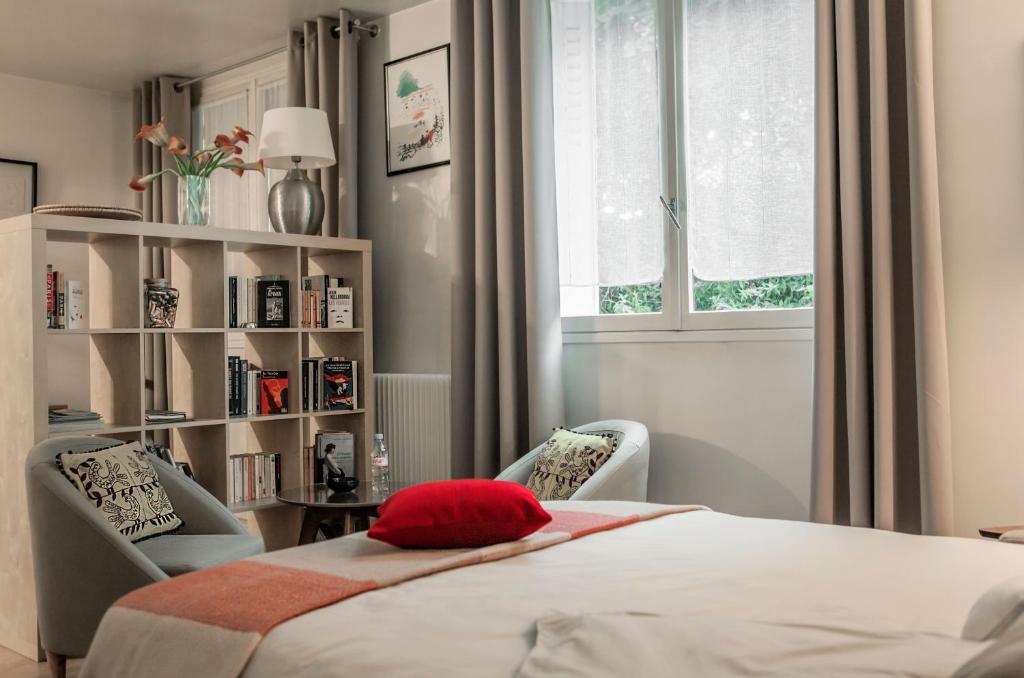 a bedroom with a bed and two chairs and a book shelf at Le Studio 1517 in Le Kremlin-Bicêtre
