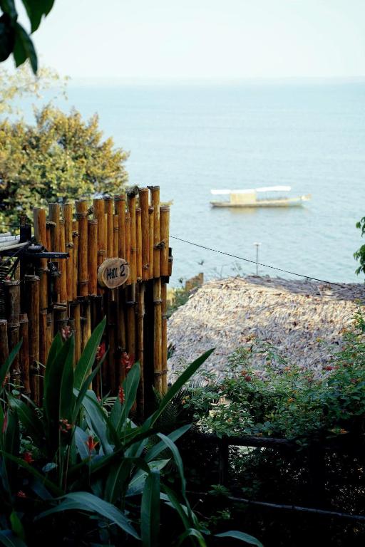 a wooden fence with a boat in the water at Nomia Garden Retreats - Khu nghỉ dưỡng hồ Trị An in Xóm Ðốt Ðó