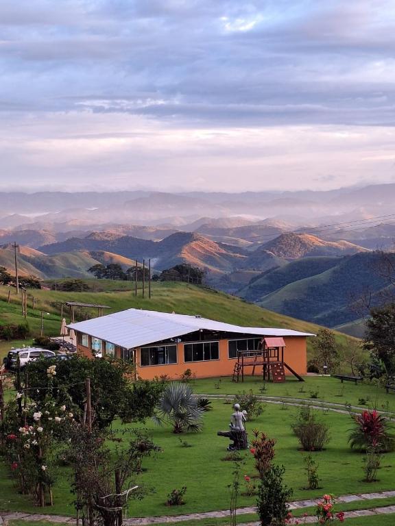 a house on a hill with mountains in the background at Pousada No Alto da Serra Conservatória in Conservatória