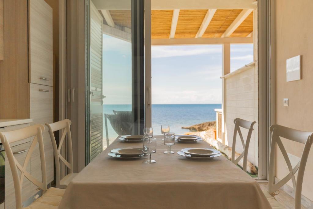 a dining table with a view of the ocean at Casetta sulla Spiaggia - HelloElba in Capoliveri