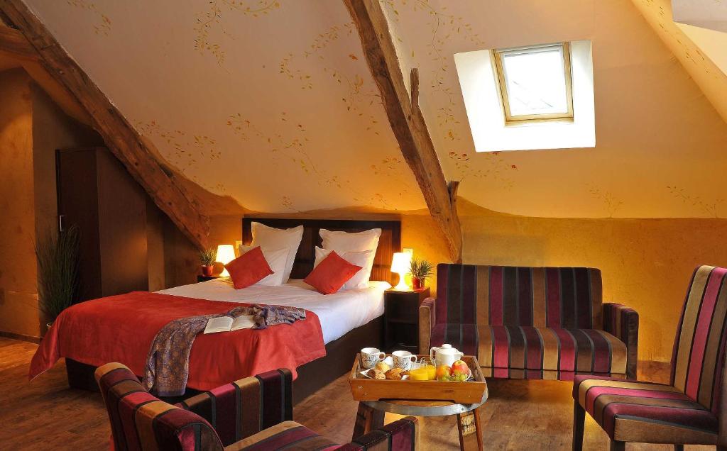 a hotel room with a bed and two chairs at Hotel O2B Aux Berges de Brocéliande in Beignon