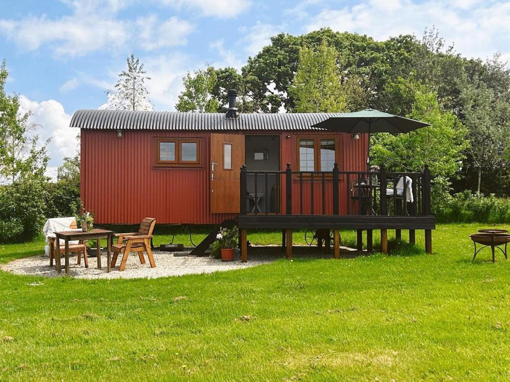 a red tiny house with a picnic table and a table at 1 Bed in Beaworthy oc-82834 in Ashwater