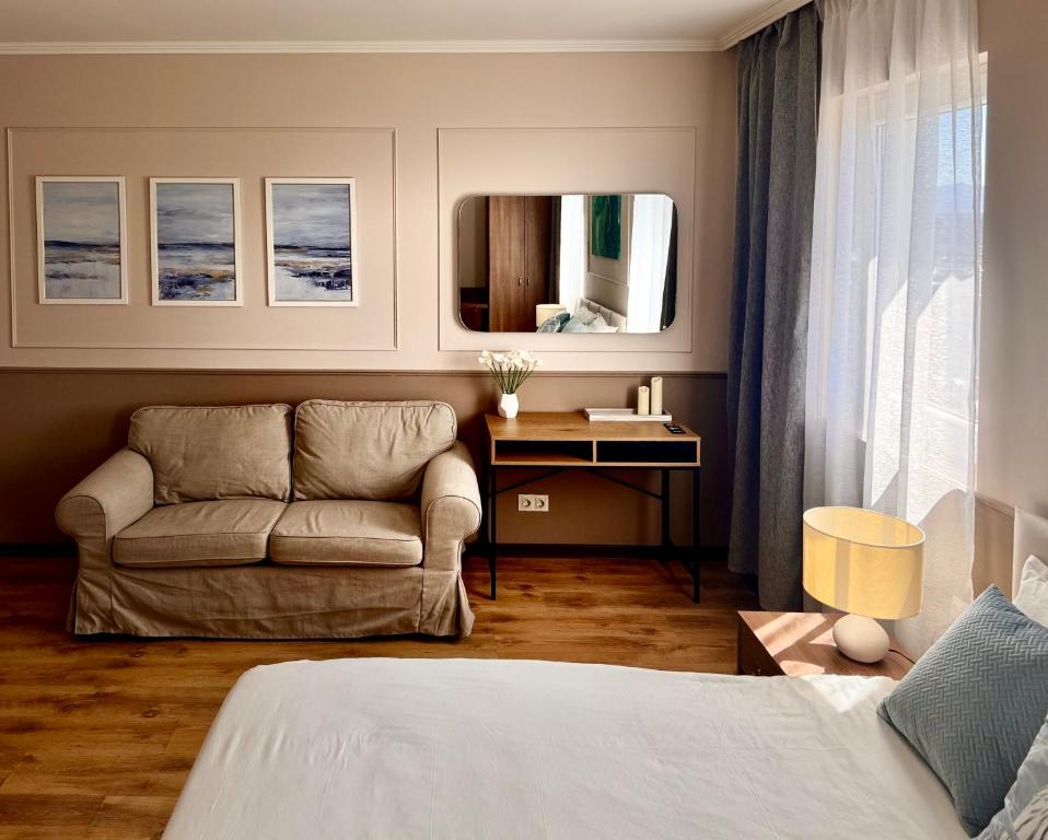 a bedroom with a bed and a couch and a mirror at AirportStay bg - free shuttle and own parking in Sofia