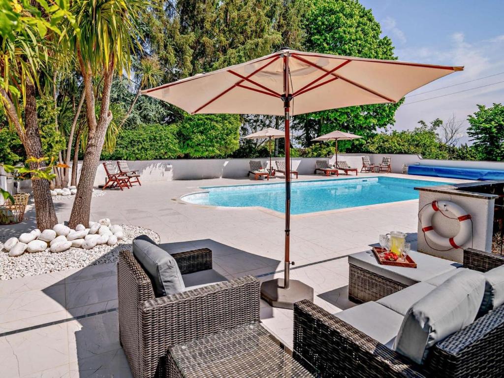 a patio with chairs and an umbrella next to a pool at 2 Bed in Minehead oc-90924 in Minehead
